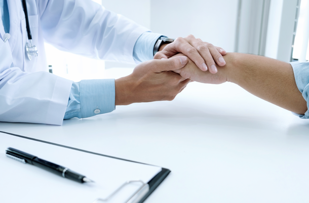 mani di un medico che abbraciano la mano di un paziente